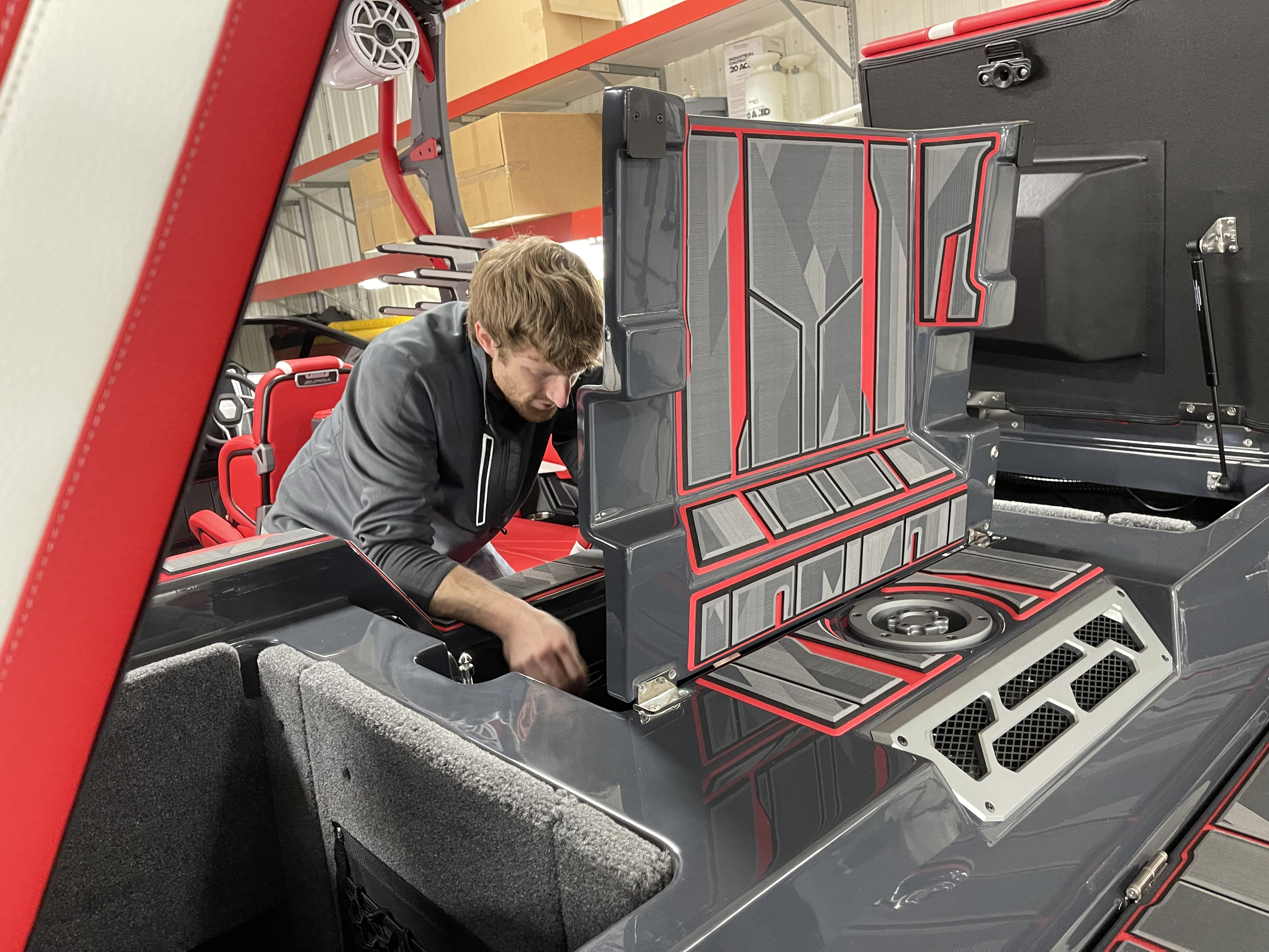 A man inside of a Supra surf boat, working on its inboard motor