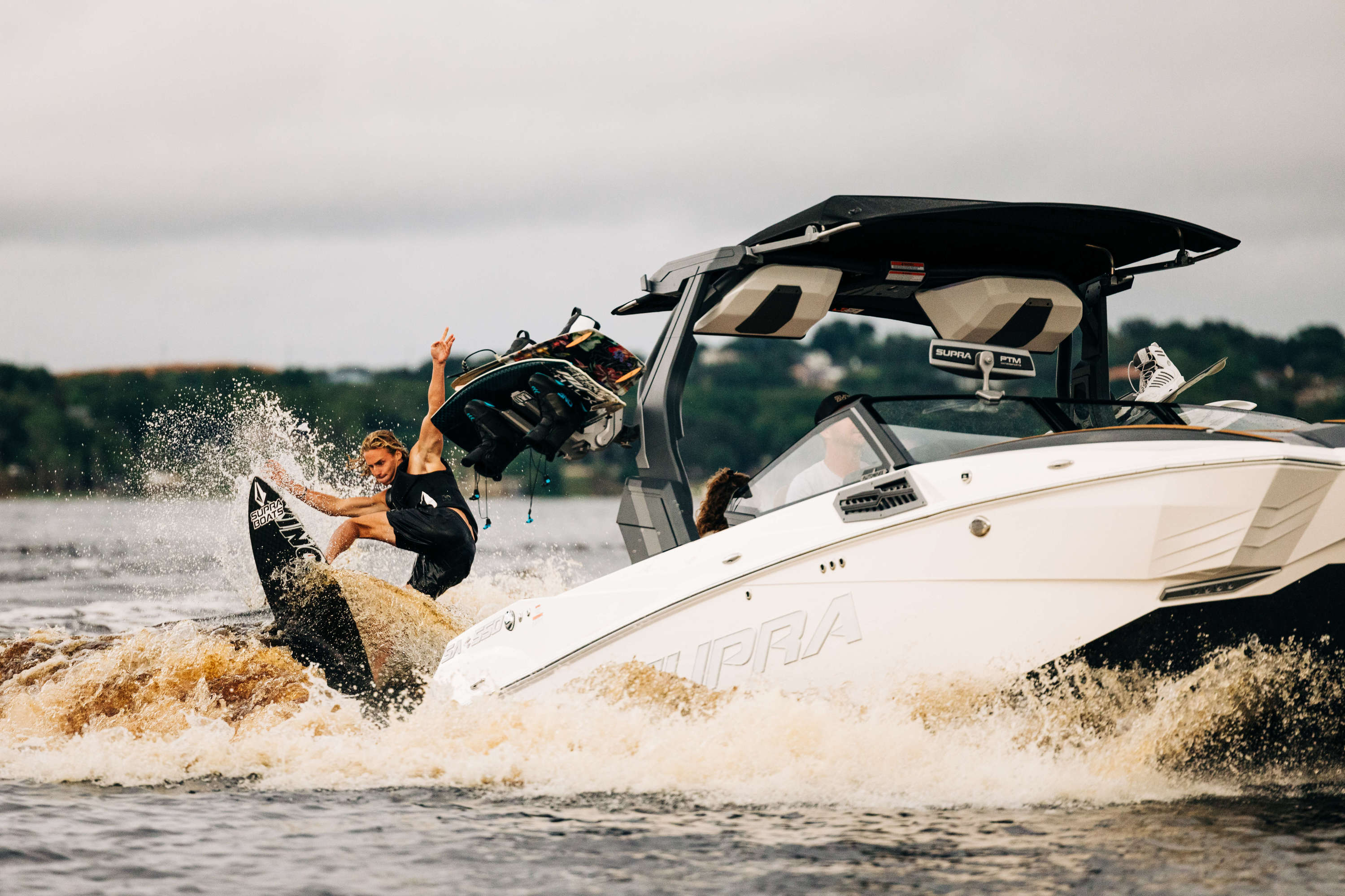 group of young riders in Moomba Makai™ all watching wakeboarder catch some air after jumping off …
